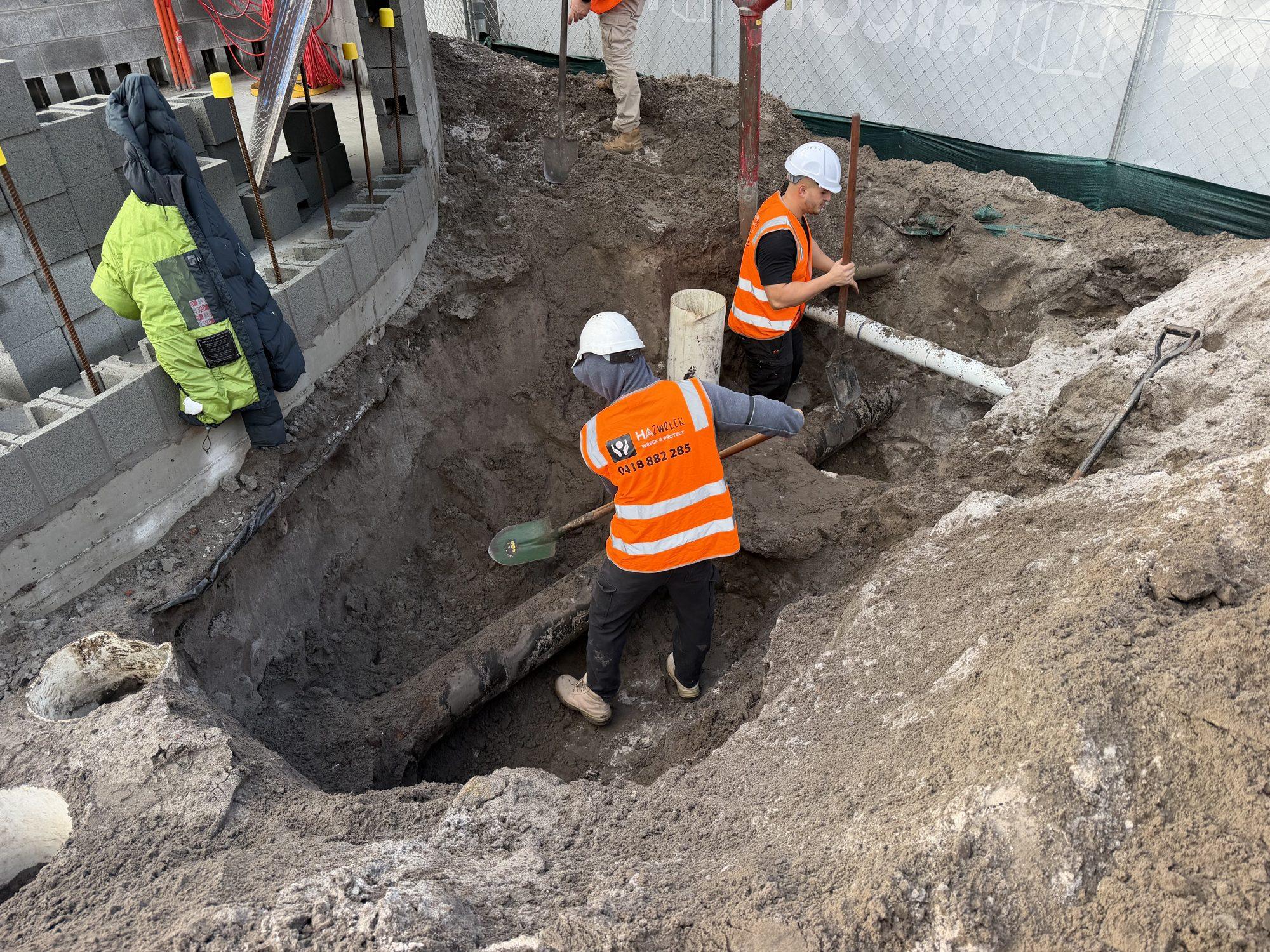 Three HazWreck crew members digging the collapsed trench back out around the water main