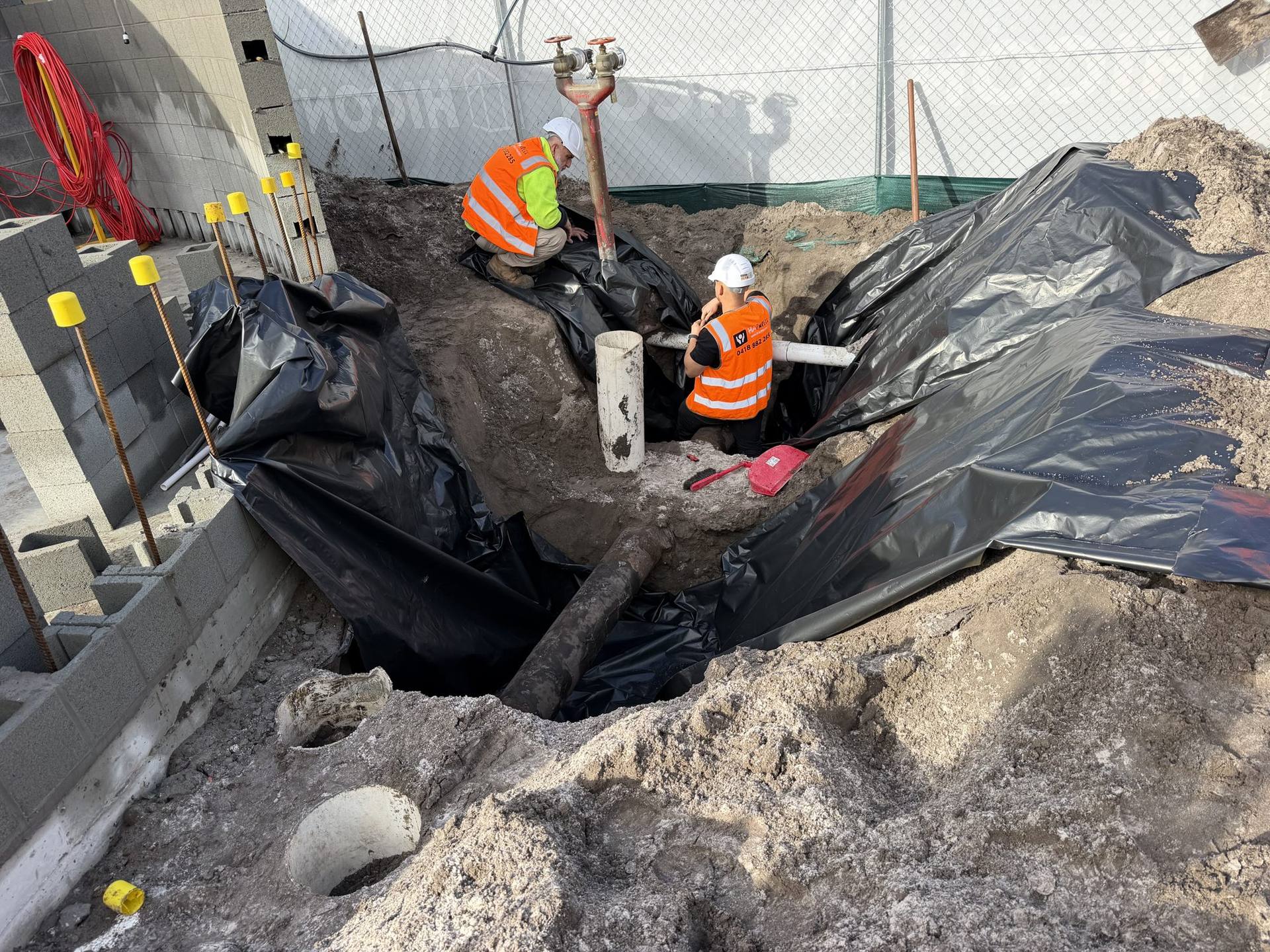 HazWreck crew lifting buried asbestos-cement pipes from a lined excavation at a Sydney Airport project