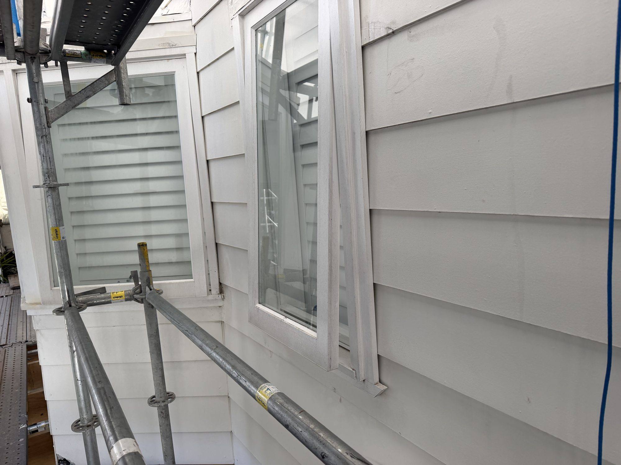 Wrapped house elevation with sealed windows during asbestos removal
