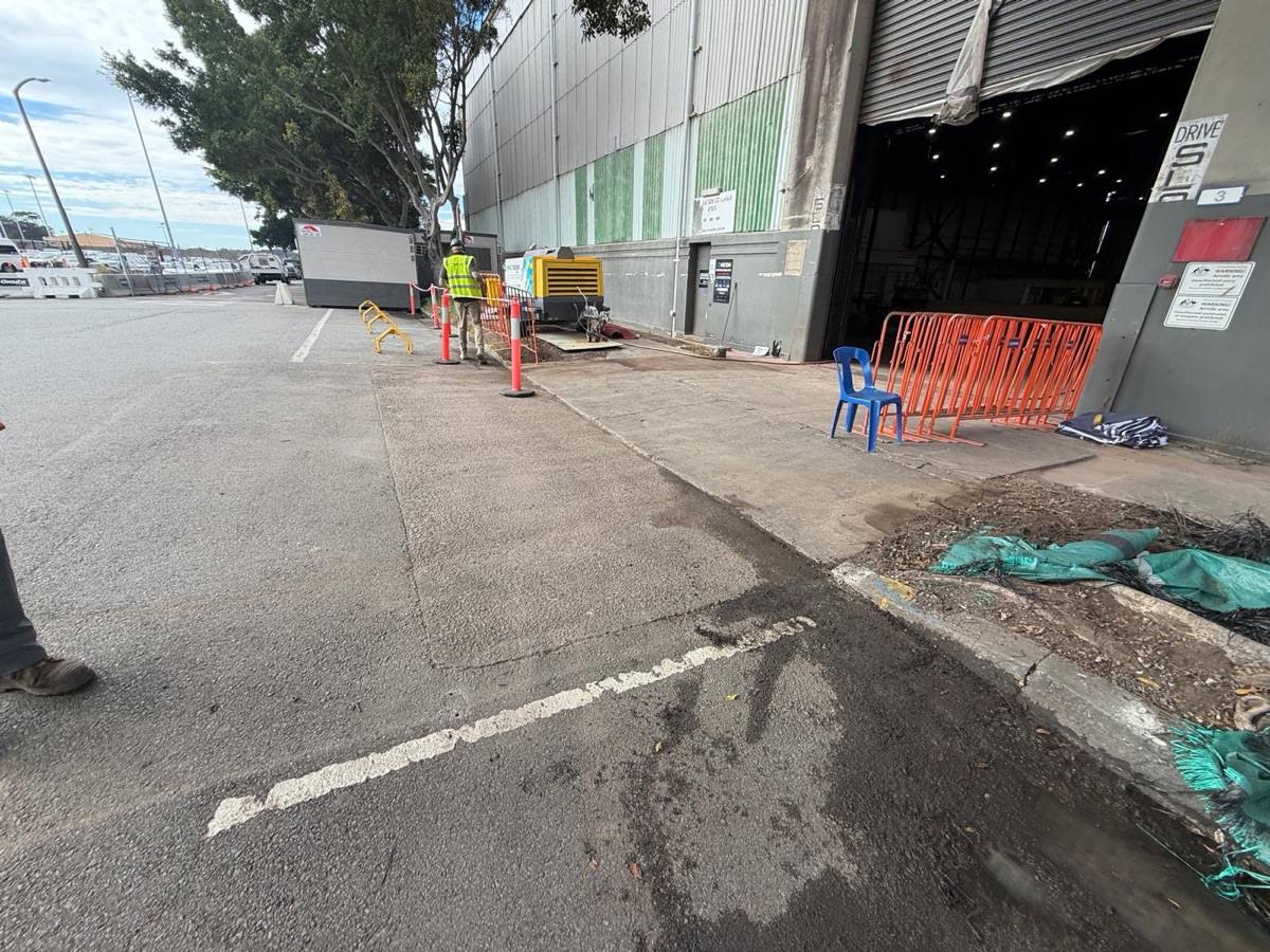 Cleaned footpath and hangar entry at Sydney Airport with fence panels stacked for collection at handover