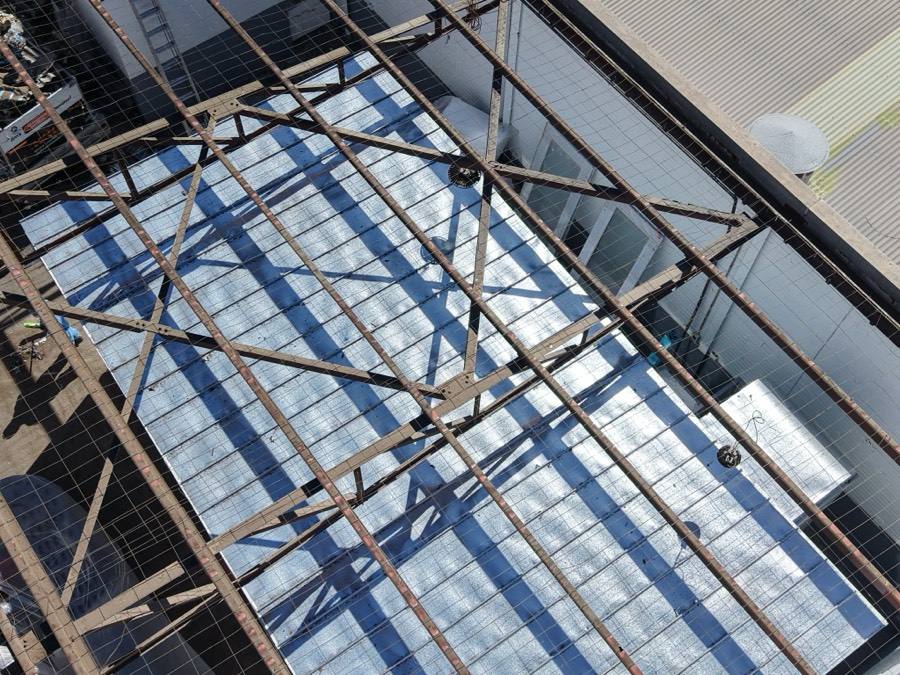 Aerial view of a warehouse roof structure being stripped