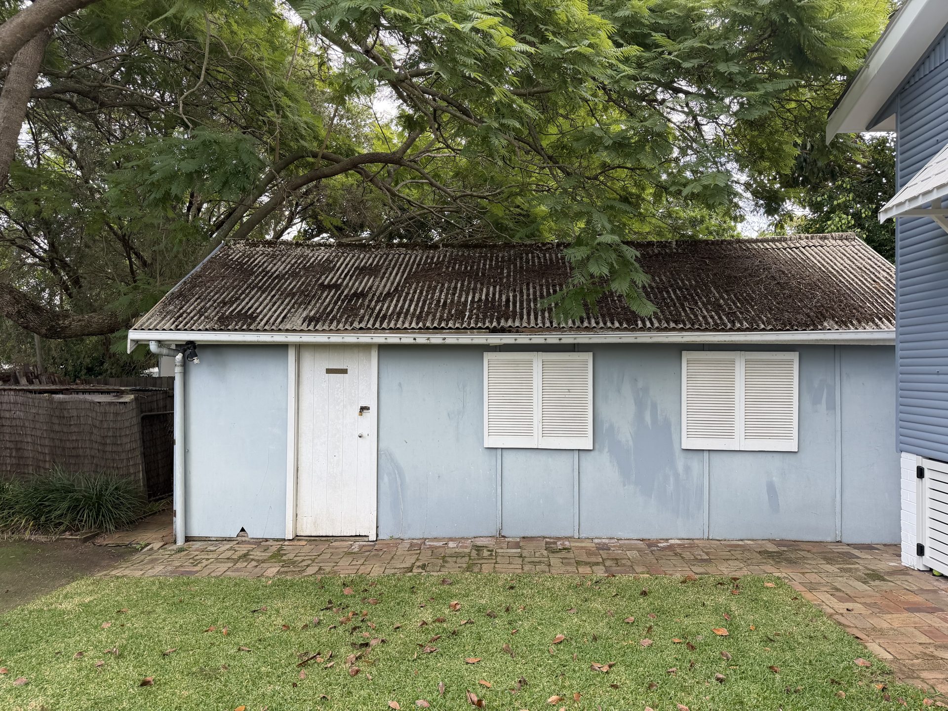 Blue fibro garage with a weathered Super Six asbestos-cement roof in Northmead before demolition