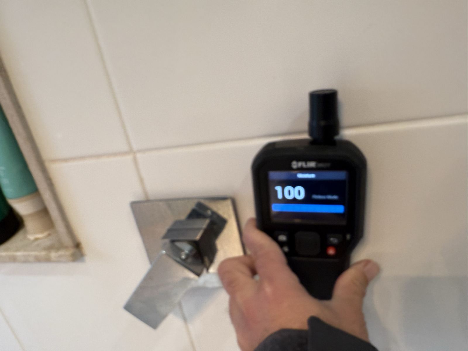 Moisture meter reading 100 on a tiled bathroom wall during a mould inspection in a Dural home